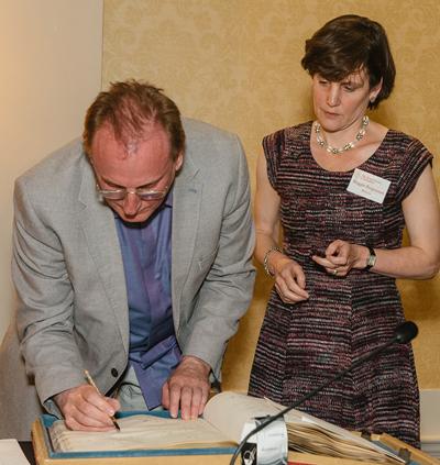 Professor Ray Monk formally signing the RSL roll book, alongside its Director Maggie Fergusson.